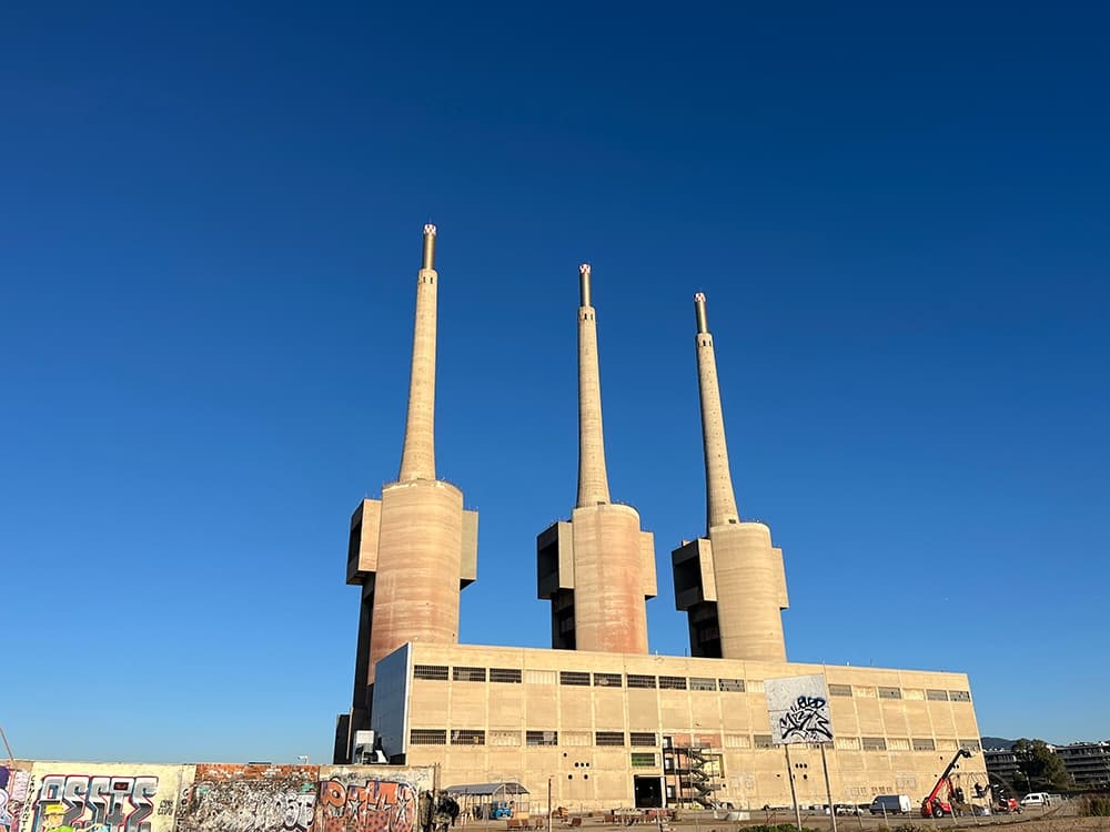 Industrial power plant chimneys under blue sky on coastal plain