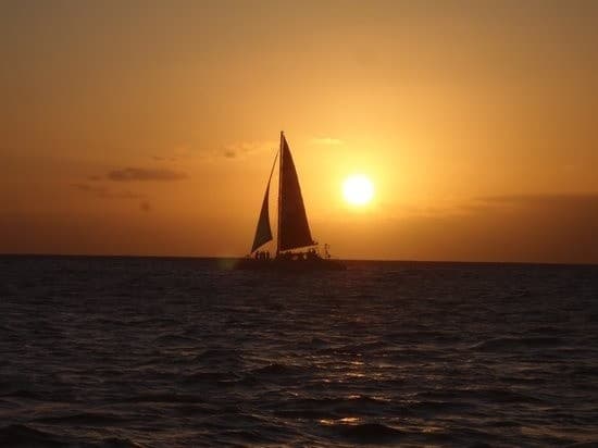 Sailboat silhouette cruising at sunset on open ocean