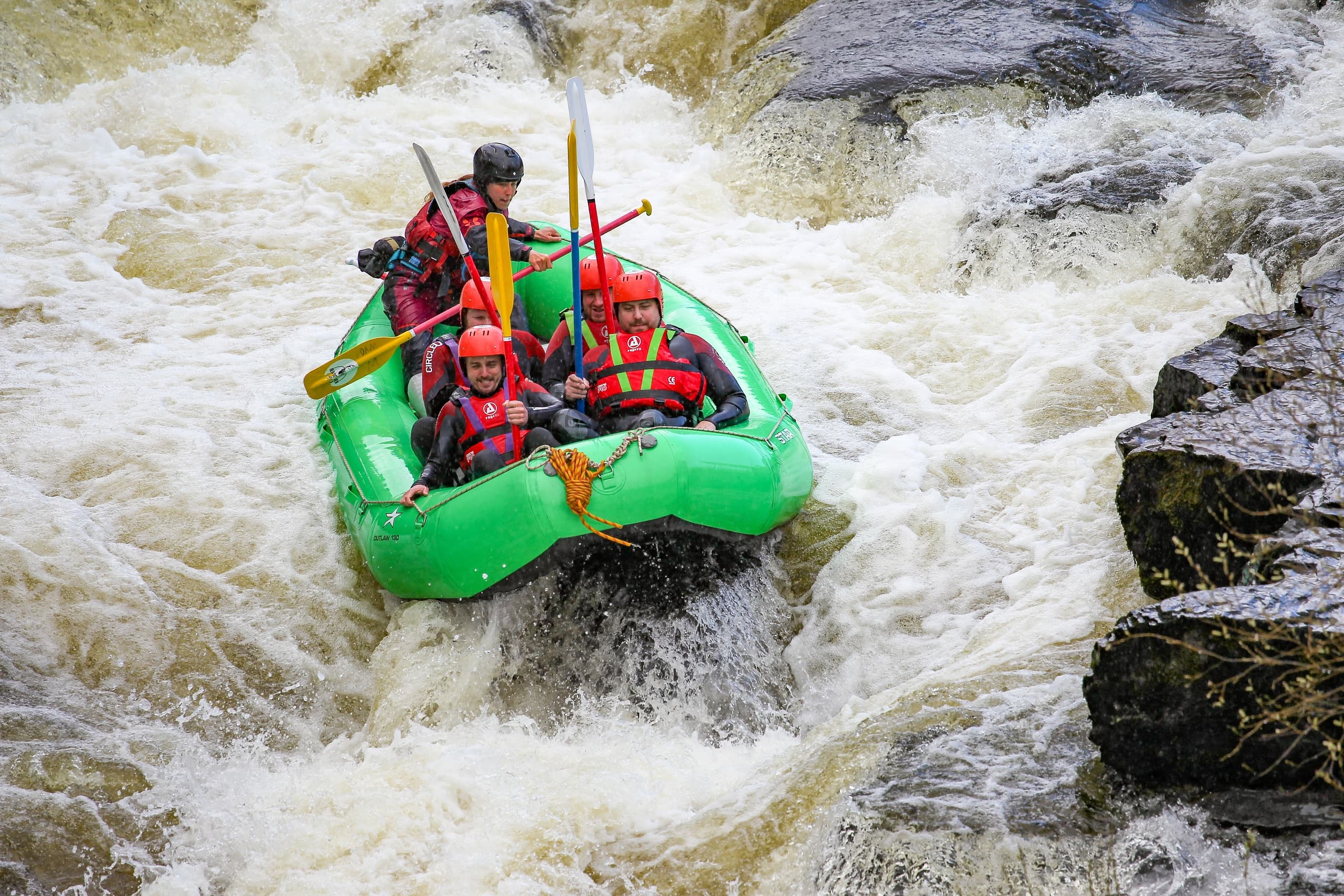 Whitewater rafting in rocky rapids, team navigating turbulent water