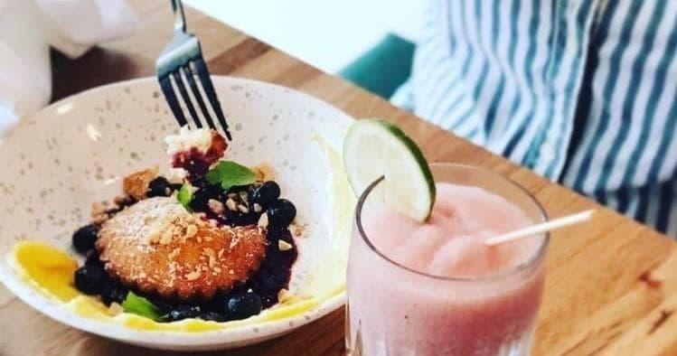 Brunch plate with fried pastry and smoothie at cafe table