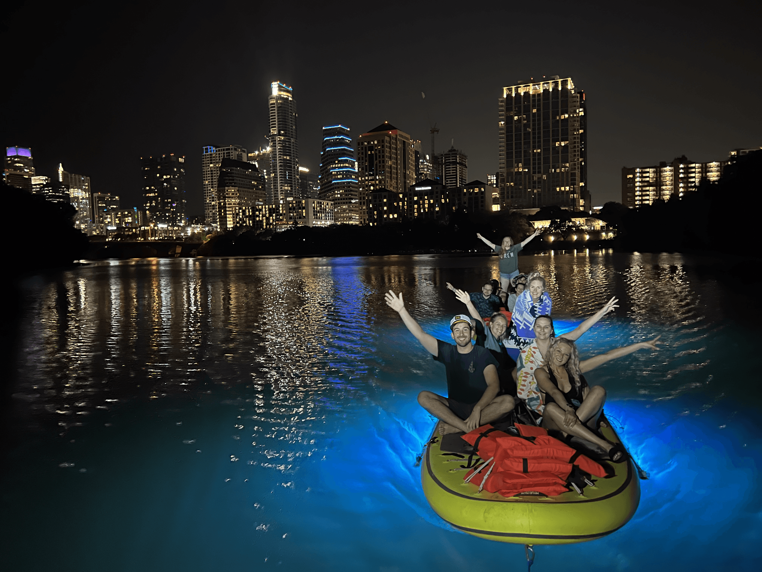 Nighttime inflatable boat lit by LED lights on city lake