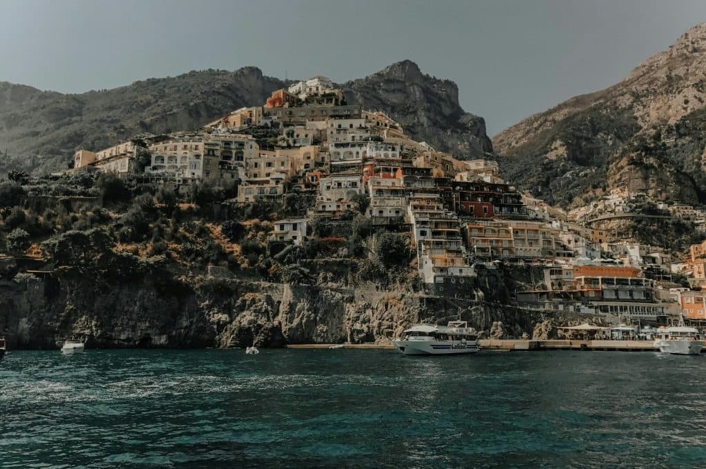 Coastal hillside town rising above turquoise sea, boat in bay