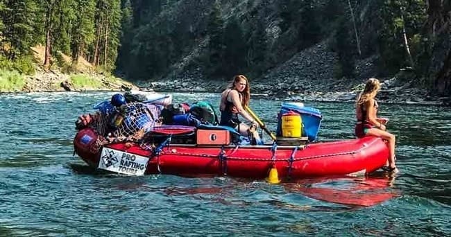 Red raft navigating scenic forested river canyon, whitewater trip