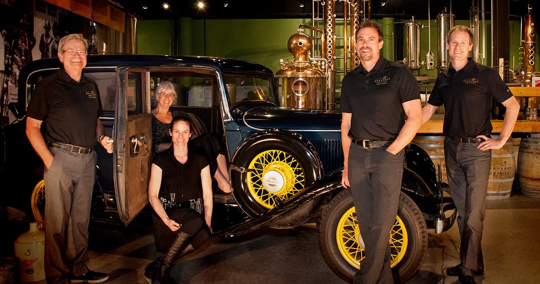 Distillery team posing with vintage car at Okanagan spirits