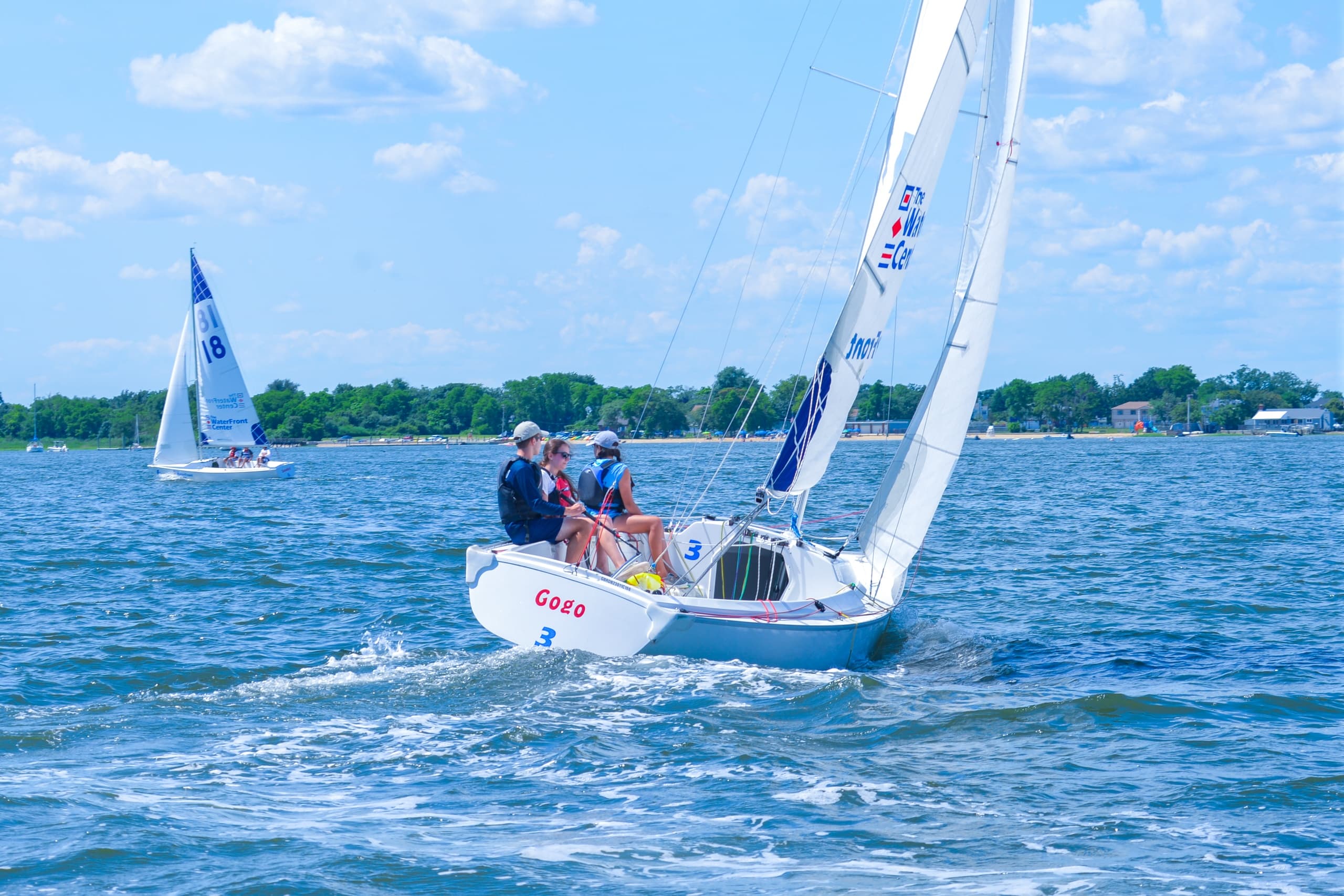 Racing keelboat crew trimming sails in coastal regatta action