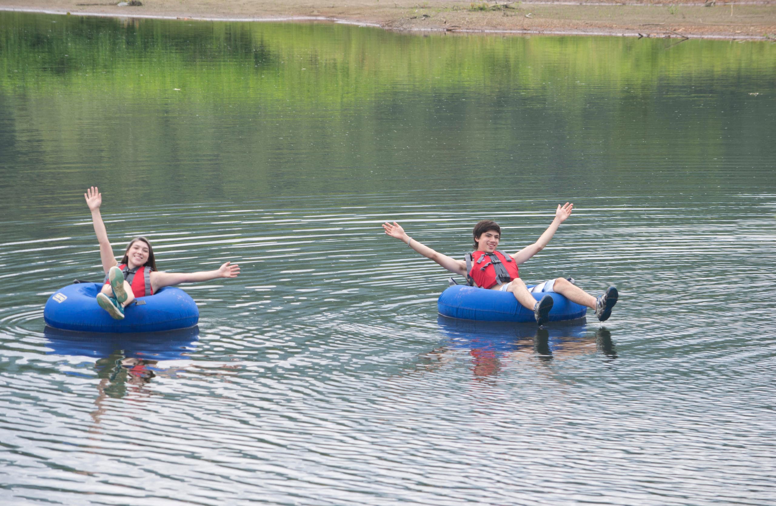 Two people tubing on a calm alpine lake enjoying summer float