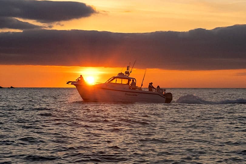 Sunset boat silhouette cruising sea on Cornwall coast tour