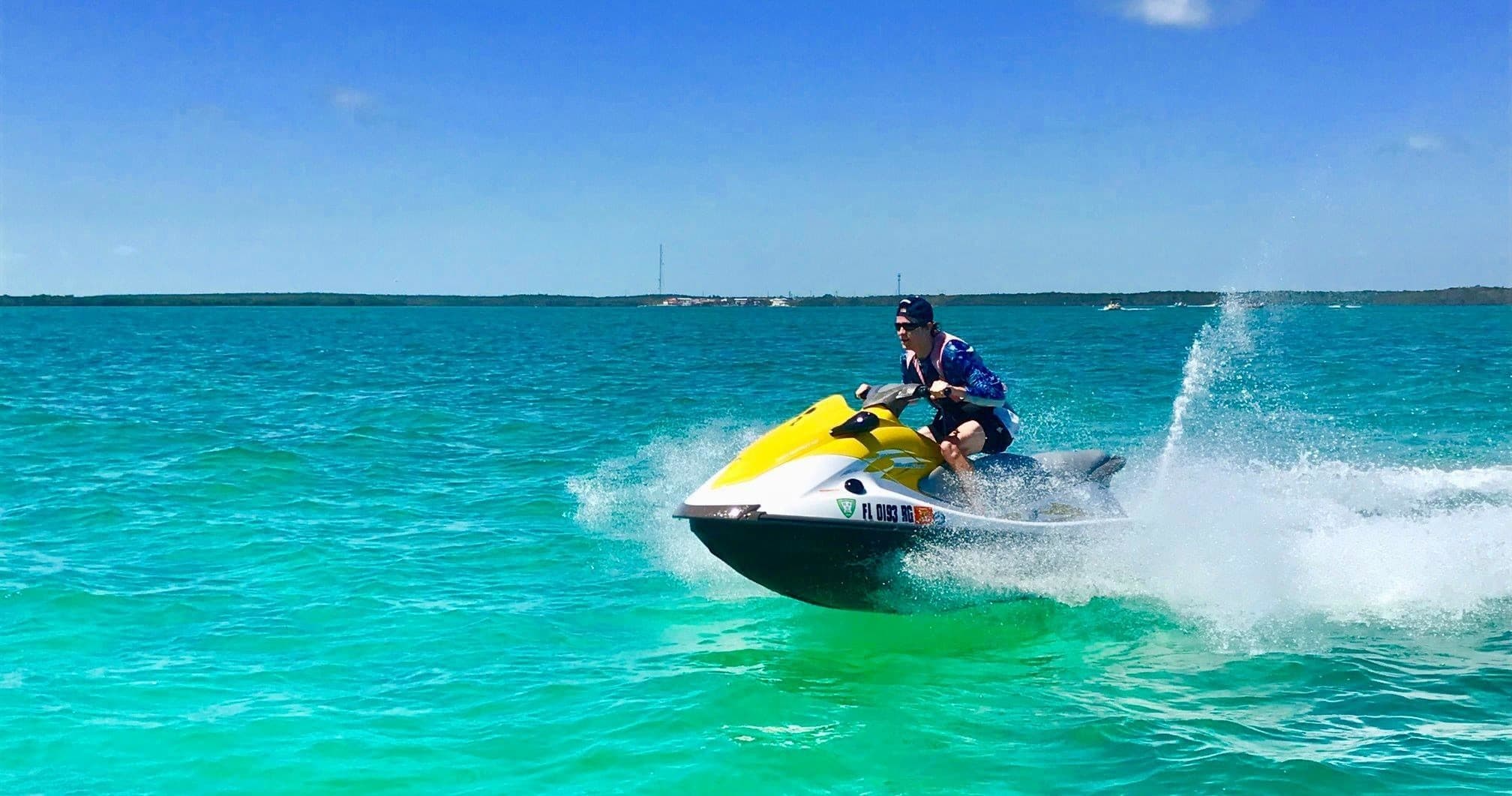 Solo rider cutting through turquoise sea on yellow jet ski