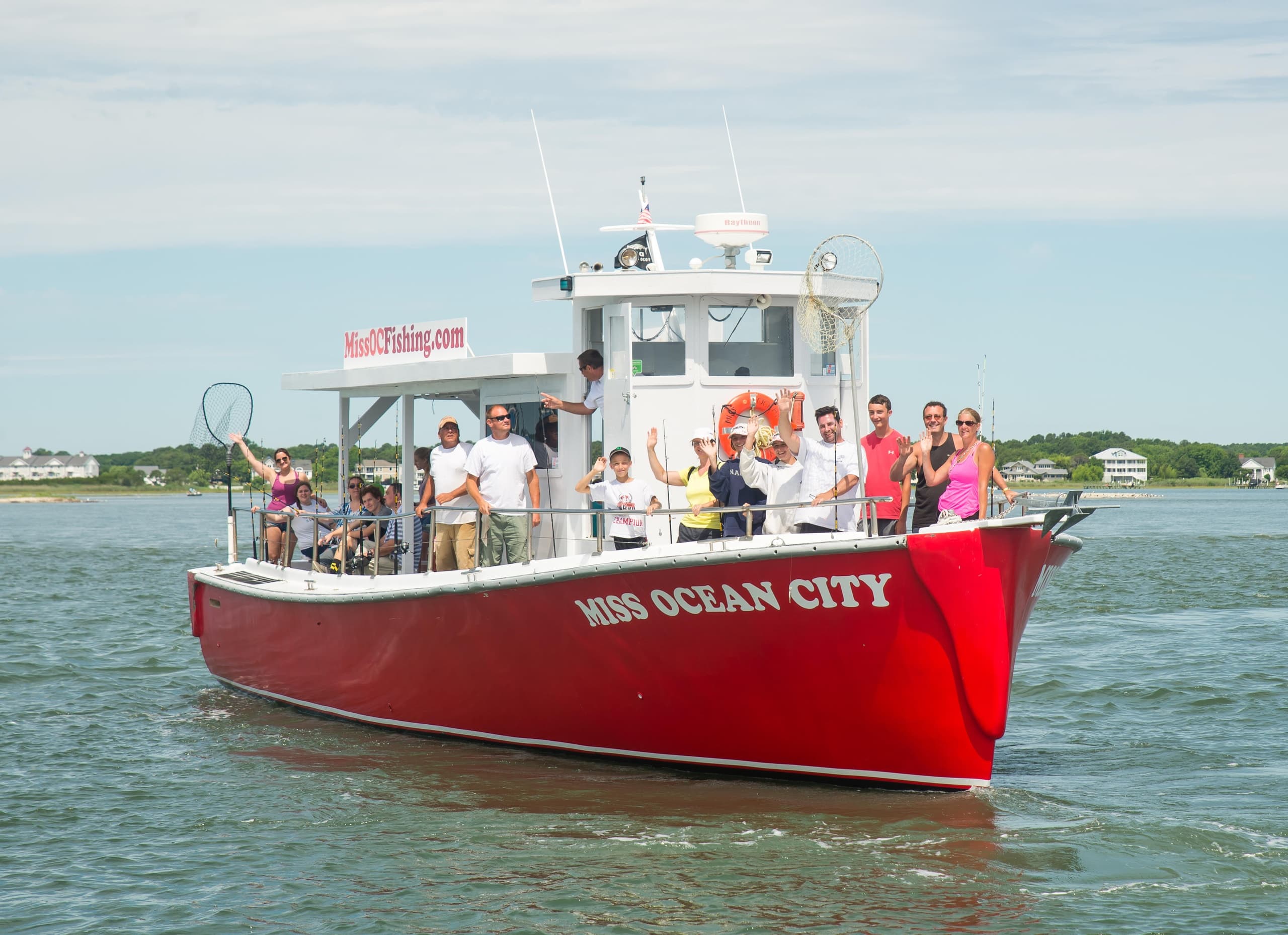 Red charter boat near shore with anglers enjoying day trip