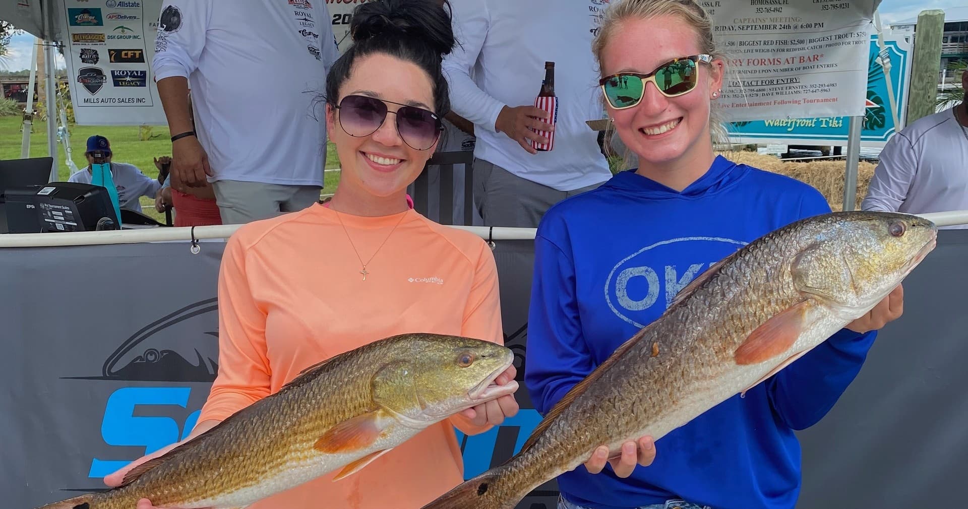 Two anglers displaying redfish at fishing tournament dockside