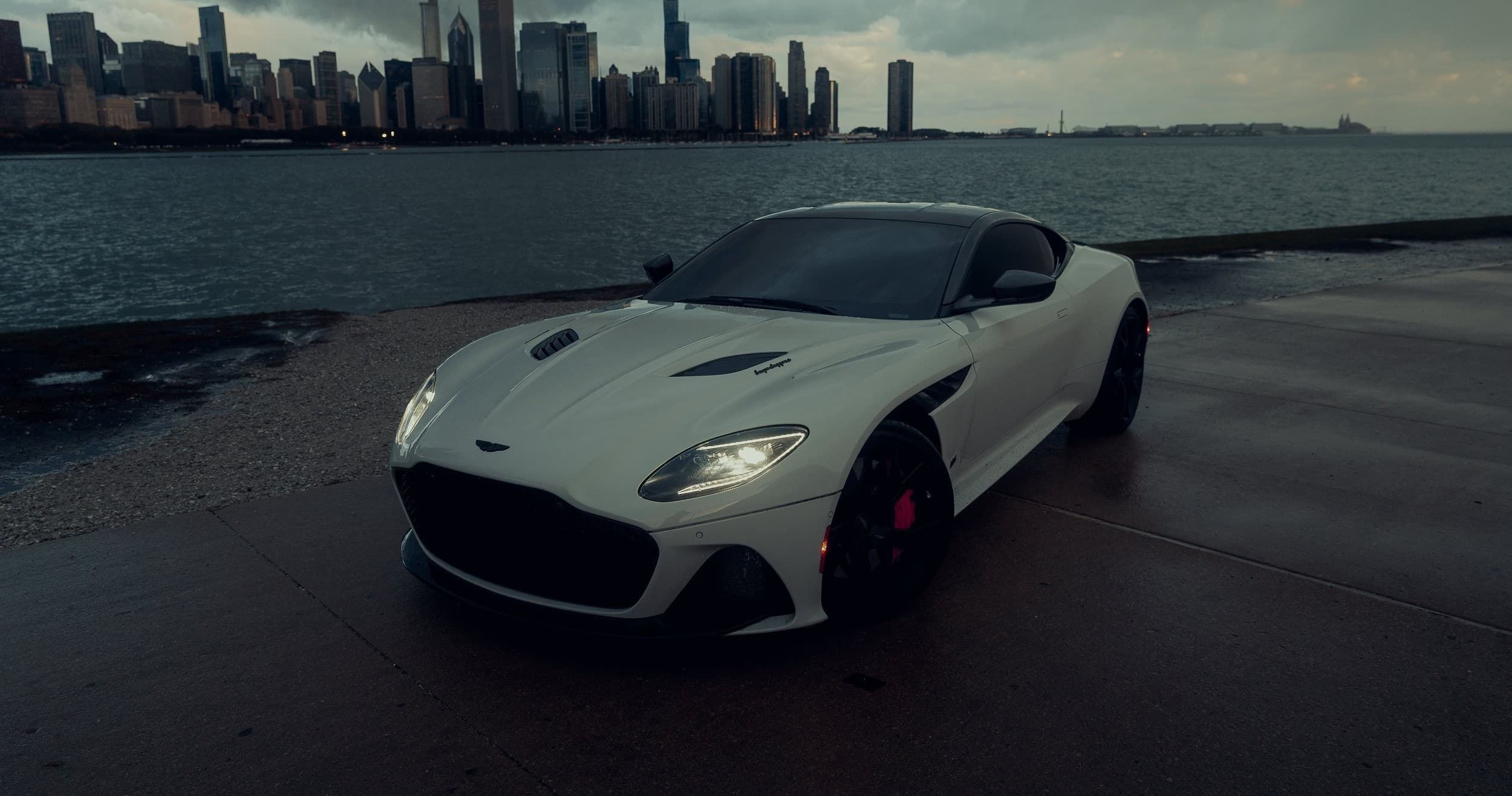 White sports car on coastal cliff road, dramatic ocean backdrop