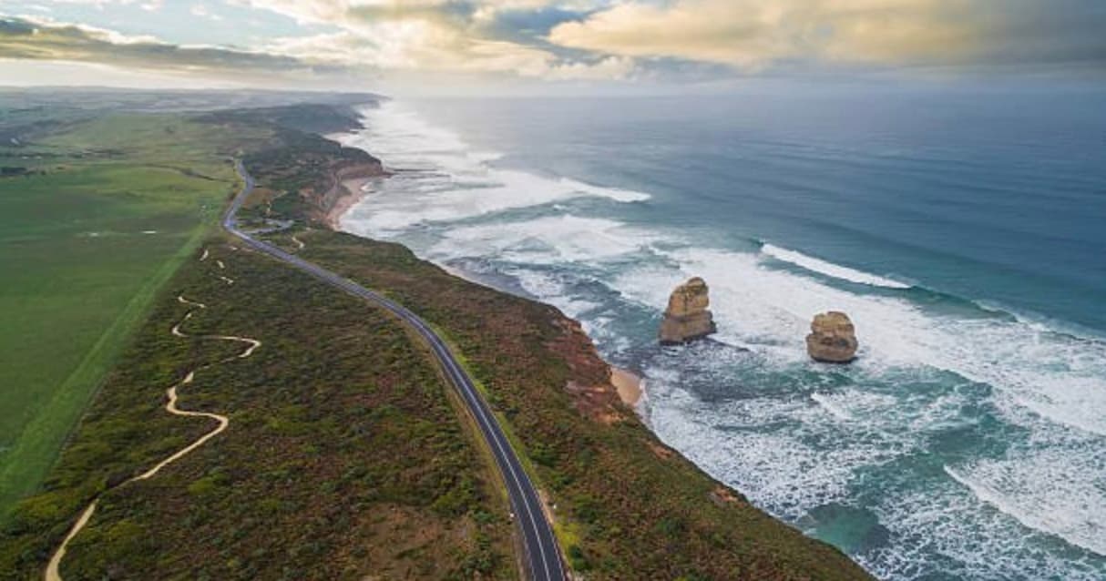 Aerial coastal road along rugged shoreline with sea stacks