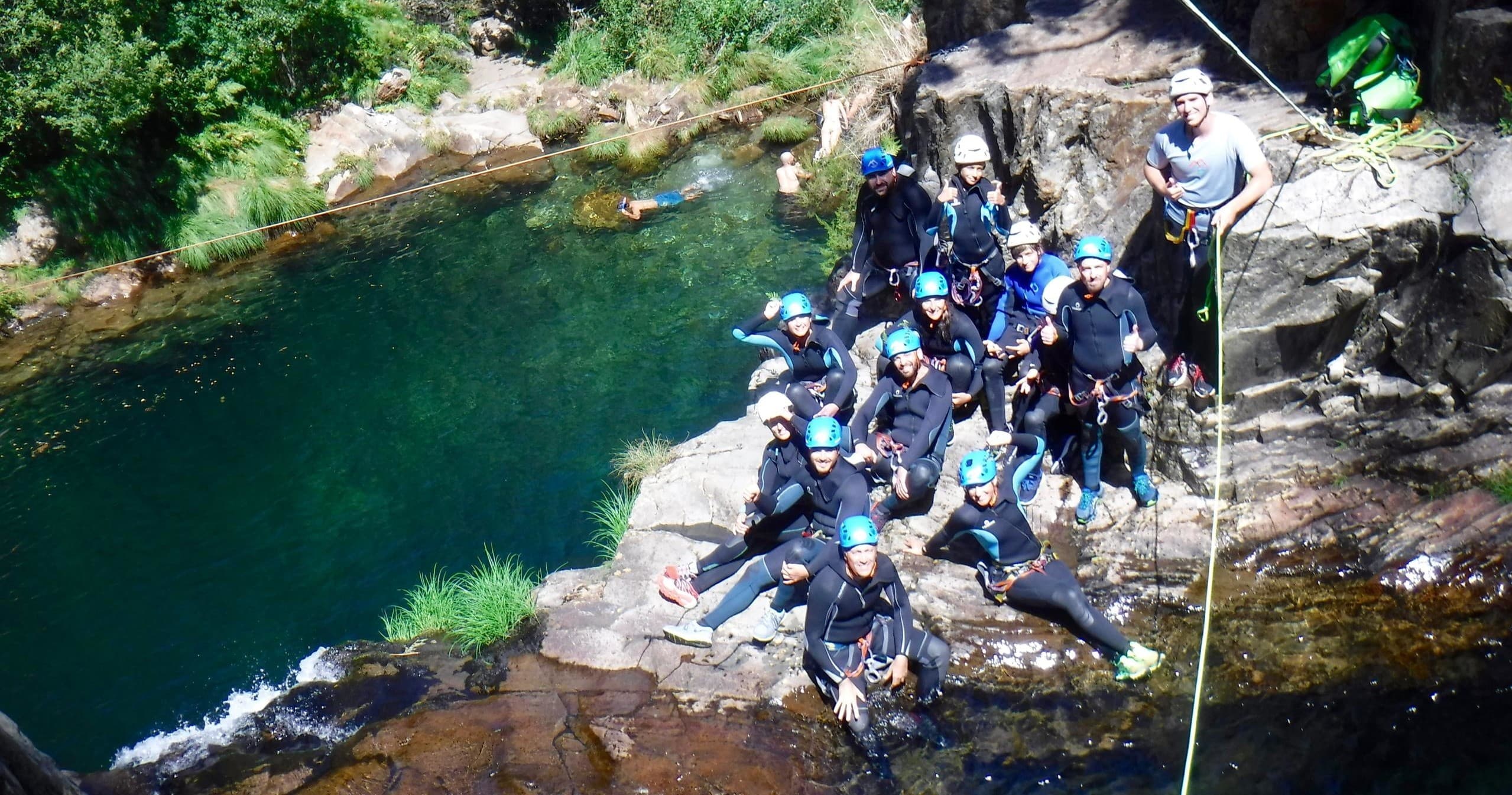 Canyoning group gathered beside emerald pool in mountain gorge