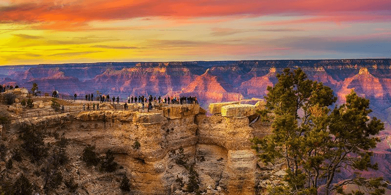 Sunset panoramic view of Grand Canyon rim with visitors watching