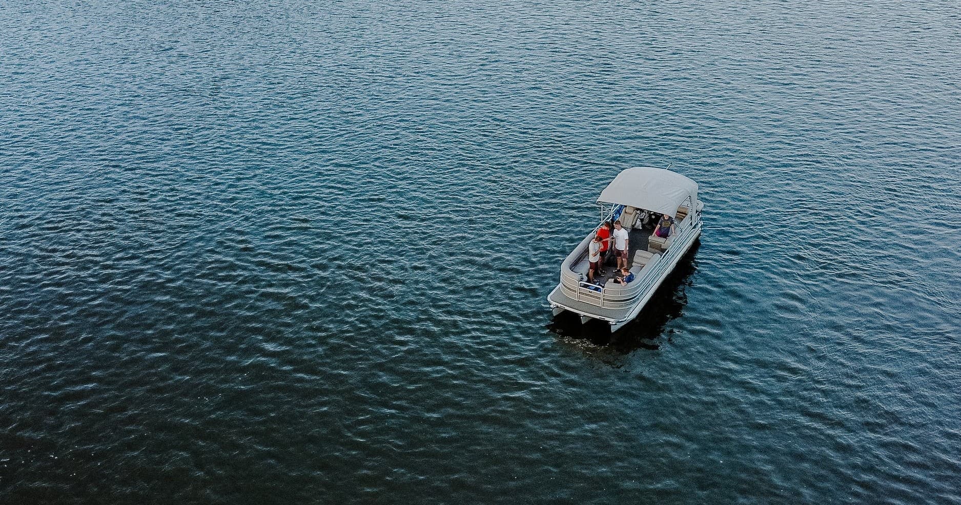 Pontoon boat with passengers cruising a calm lake for sightseeing