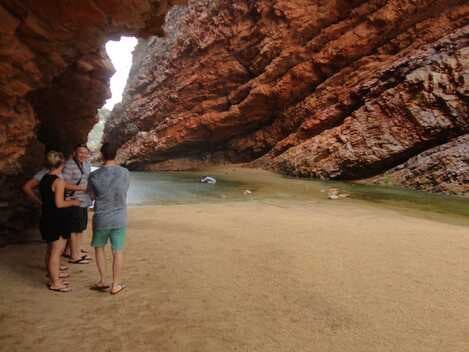 Small group admiring tranquil pool in red rock canyon amphitheater