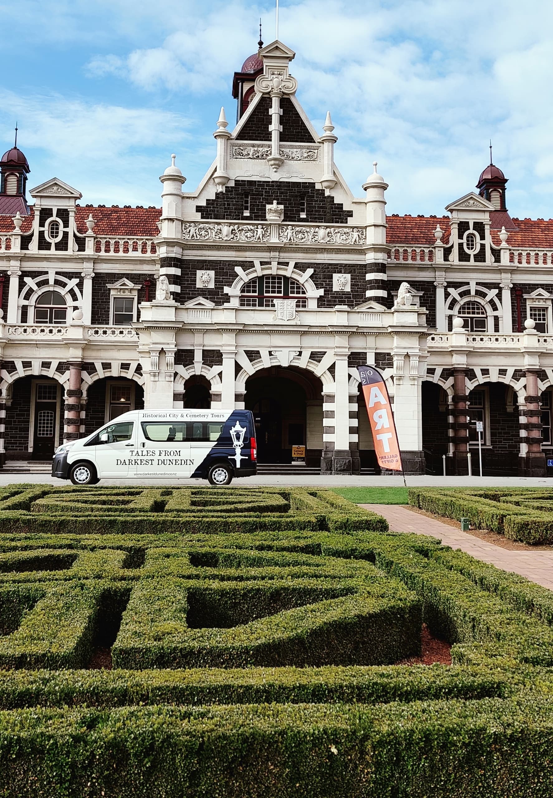 Victorian railway station facade with manicured gardens in Dunedin
