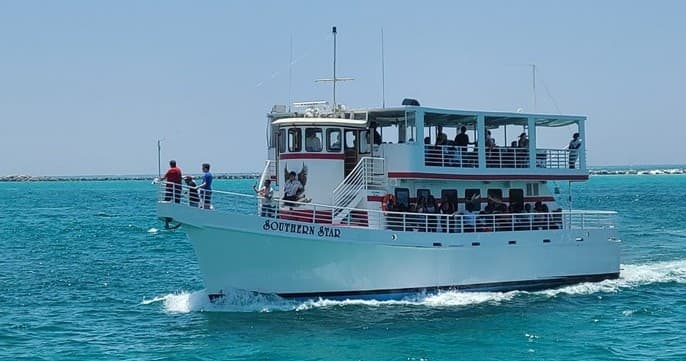 Passenger tour boat cruising clear turquoise sea near shore