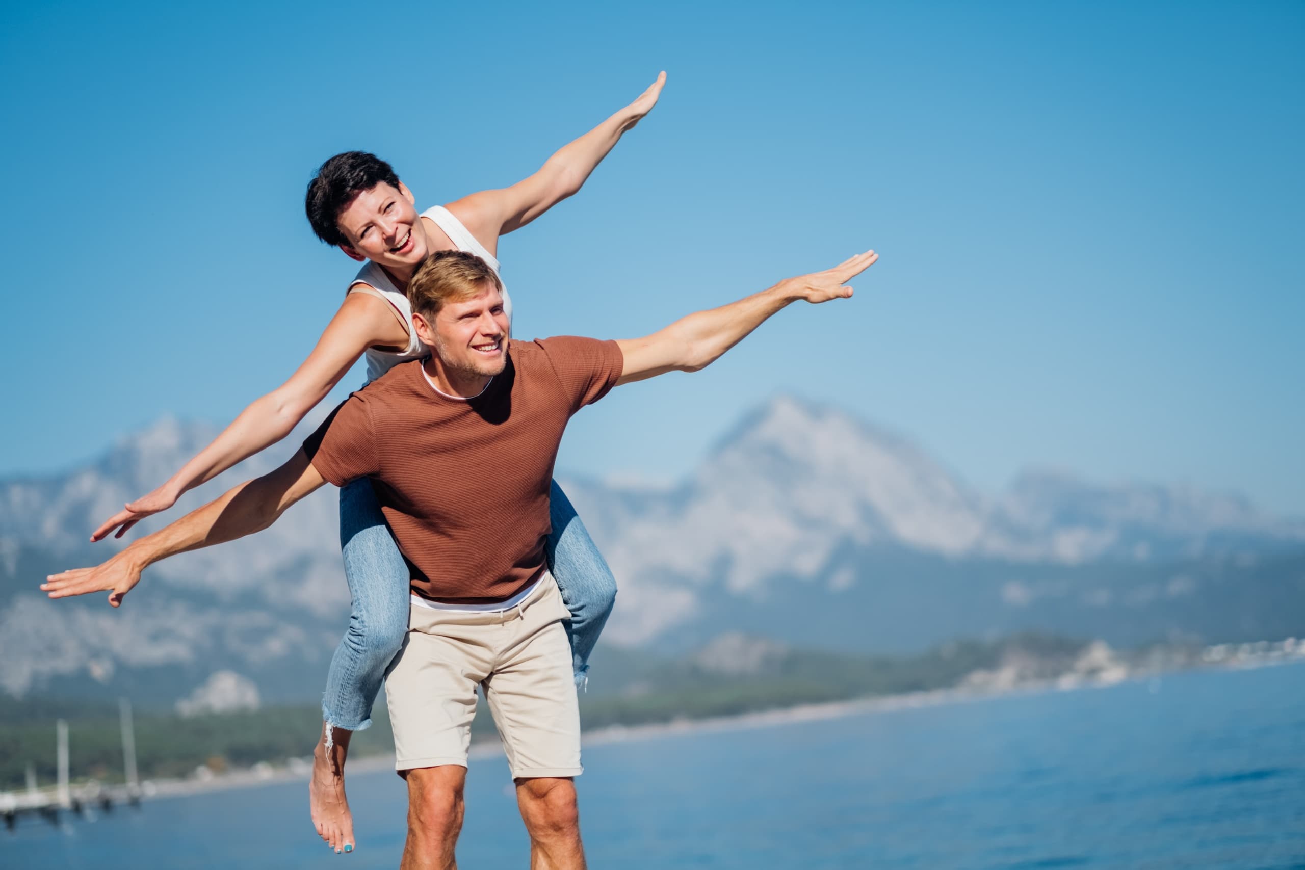 Couple enjoying beach adventure with playful piggyback by sea