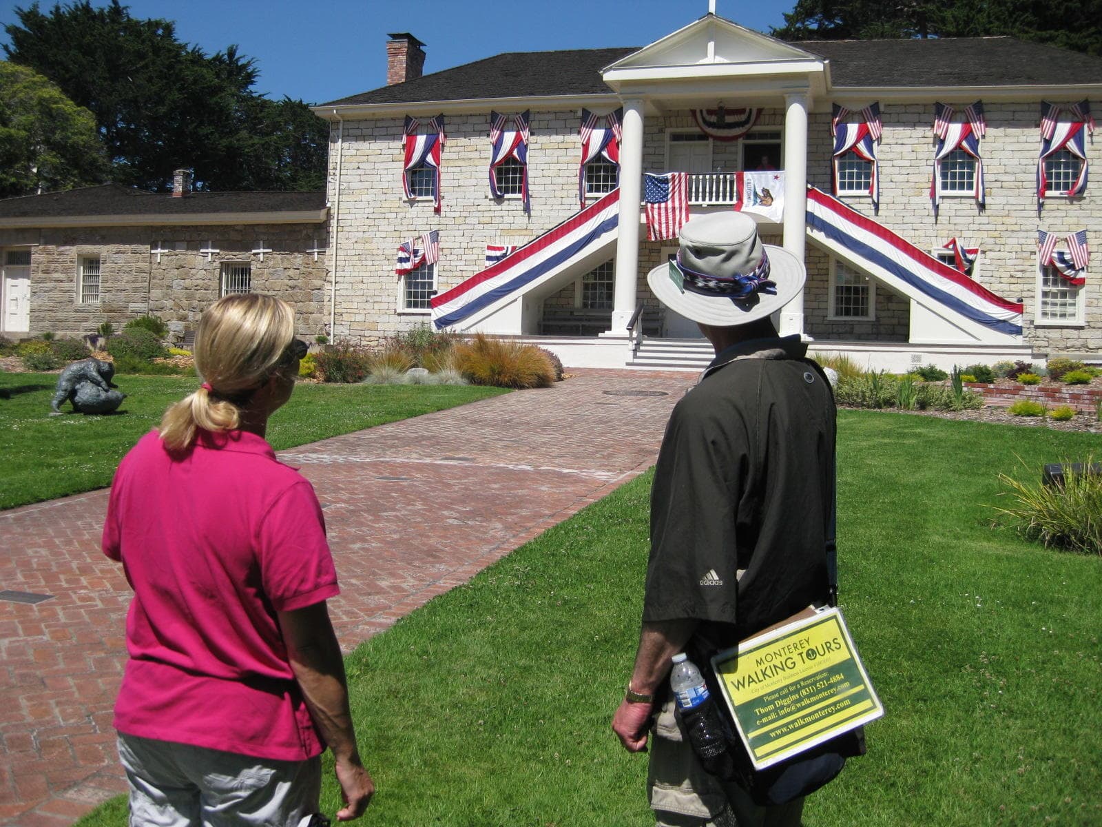 Visitors touring flag-draped historic estate grounds on Monterey walk