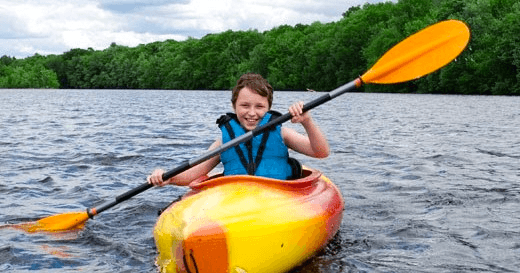 Solo kayaker paddling on a scenic, tree-lined inland lake