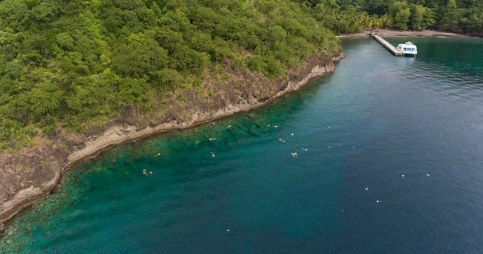 Aerial coastal cove with clear water and moored tour boat