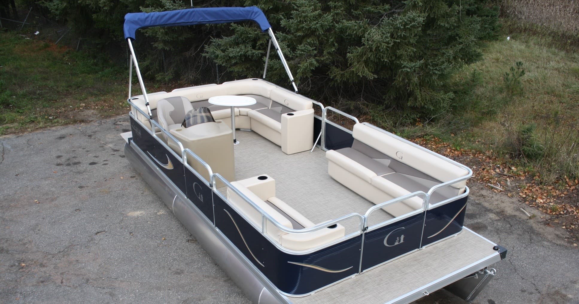 Pontoon boat parked on trailer near wooded shoreline for lake outings