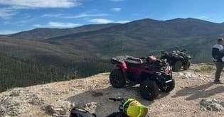 ATVs parked on mountain overlook with expansive alpine views