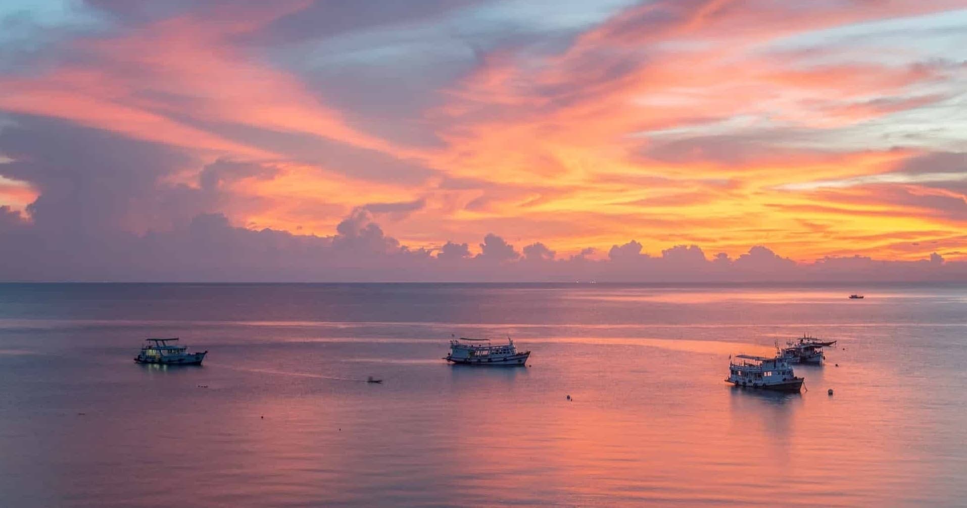 Sunset boat tour over calm tropical ocean with colorful sky
