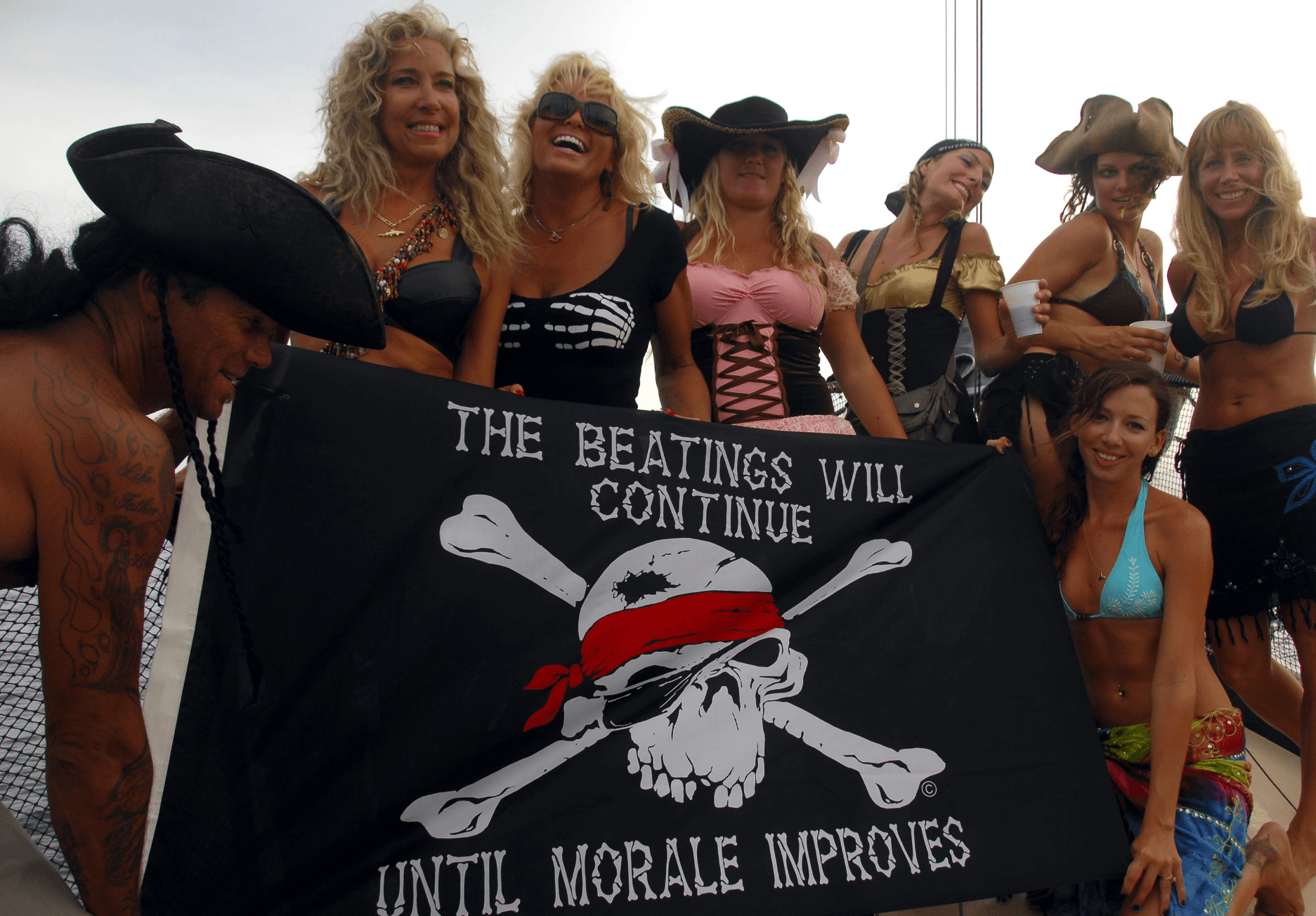 Group aboard pirate cruise holding skull flag at harbor