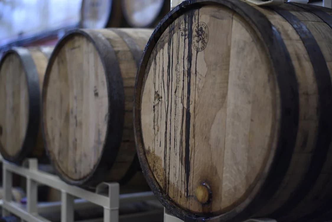 Oak whiskey barrels aging in dim cellar at craft distillery