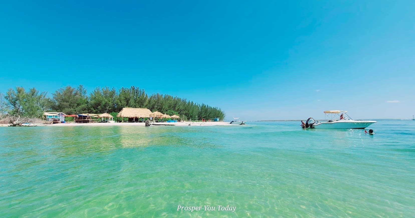 Boat tour in shallow turquoise coastal waters by tropical island
