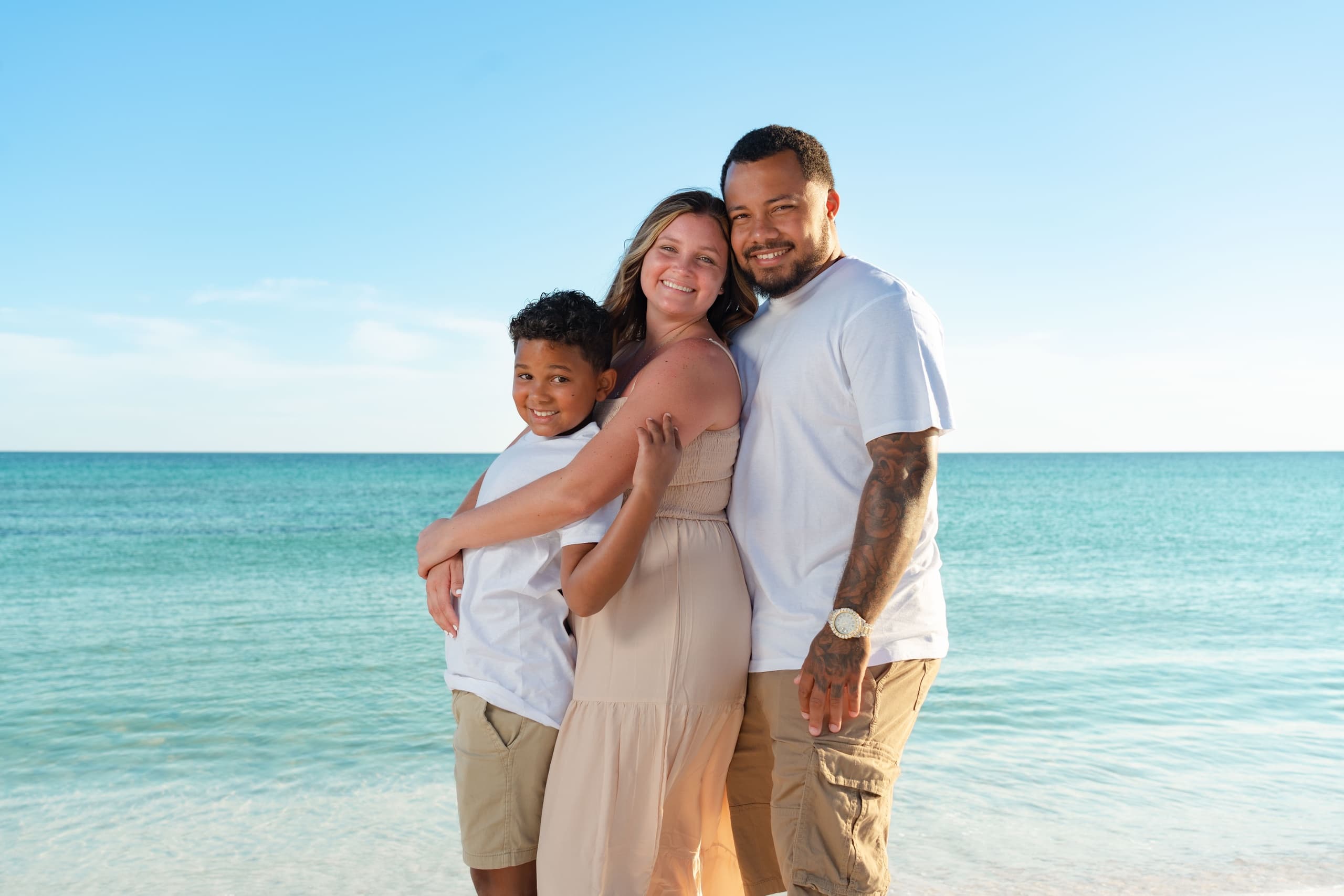 Family portrait hugging on tropical beach with turquoise sea