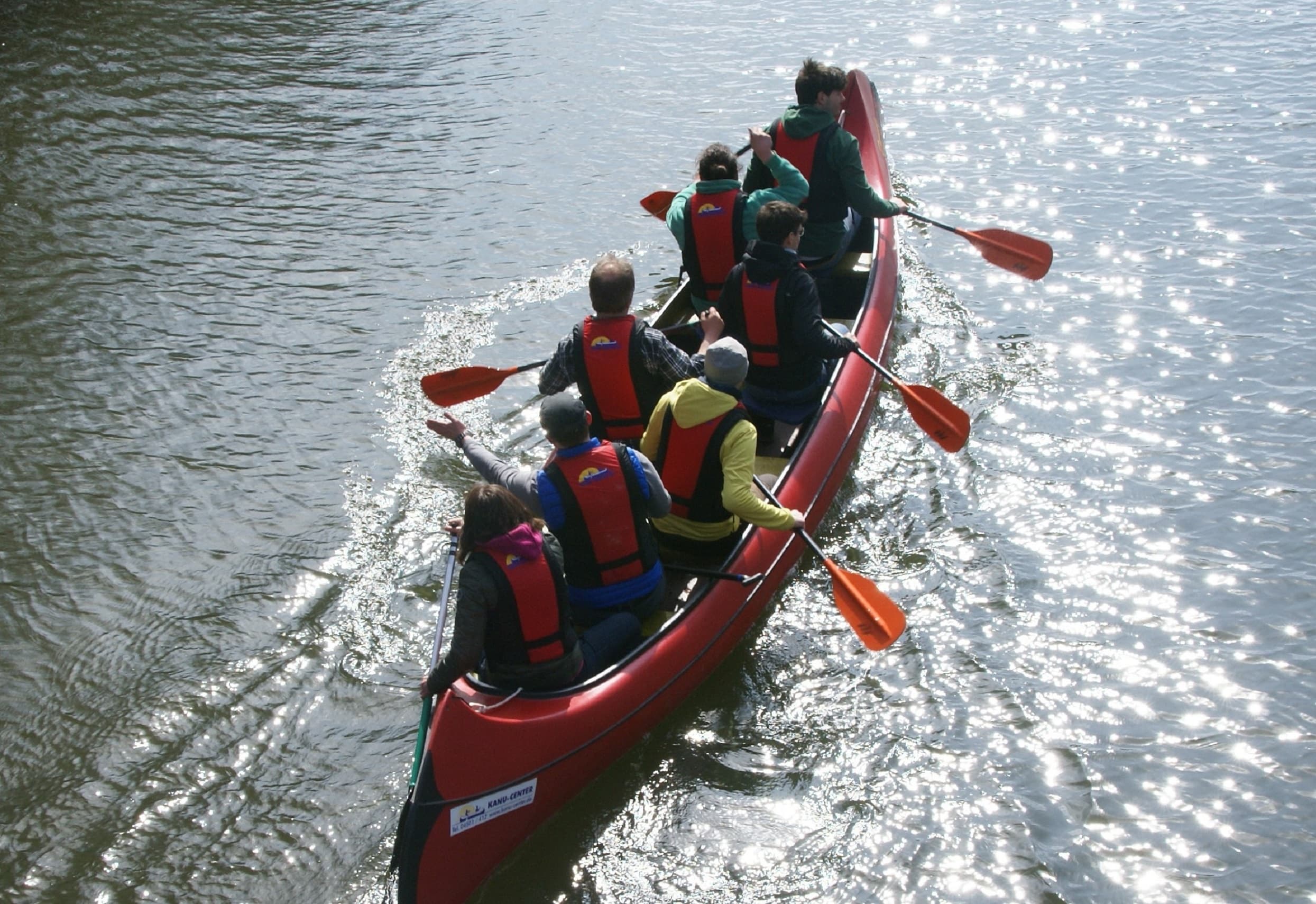 Group canoe paddling together on reflective river, team trip