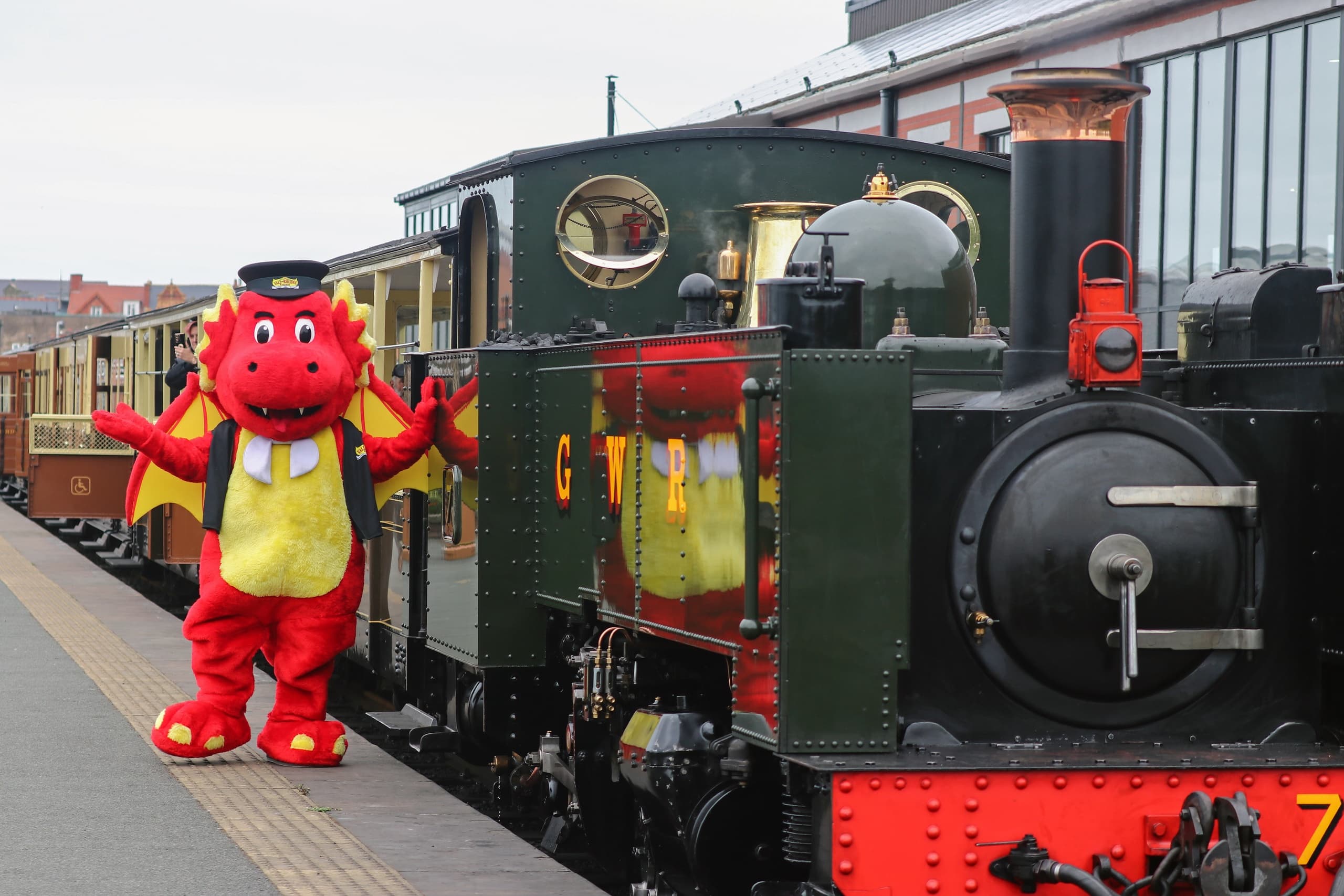 Friendly dragon mascot greeting passengers at rural station platform