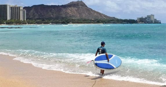 Surfer carrying a board on Waikiki beach toward Diamond Head