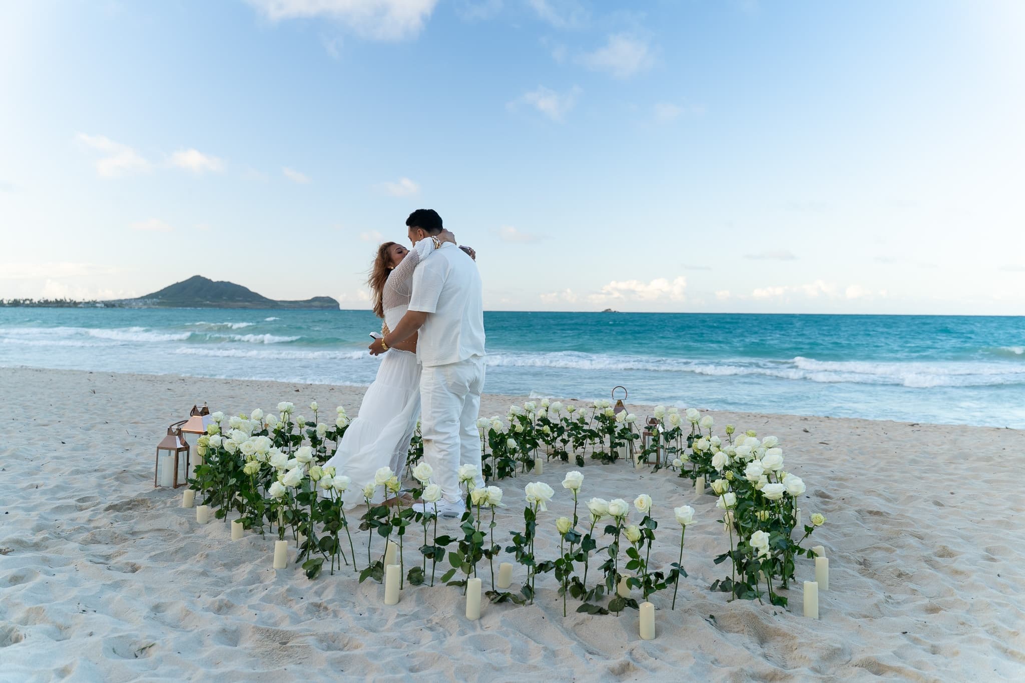 Couple embracing inside floral circle on sandy Hawaiian beach
