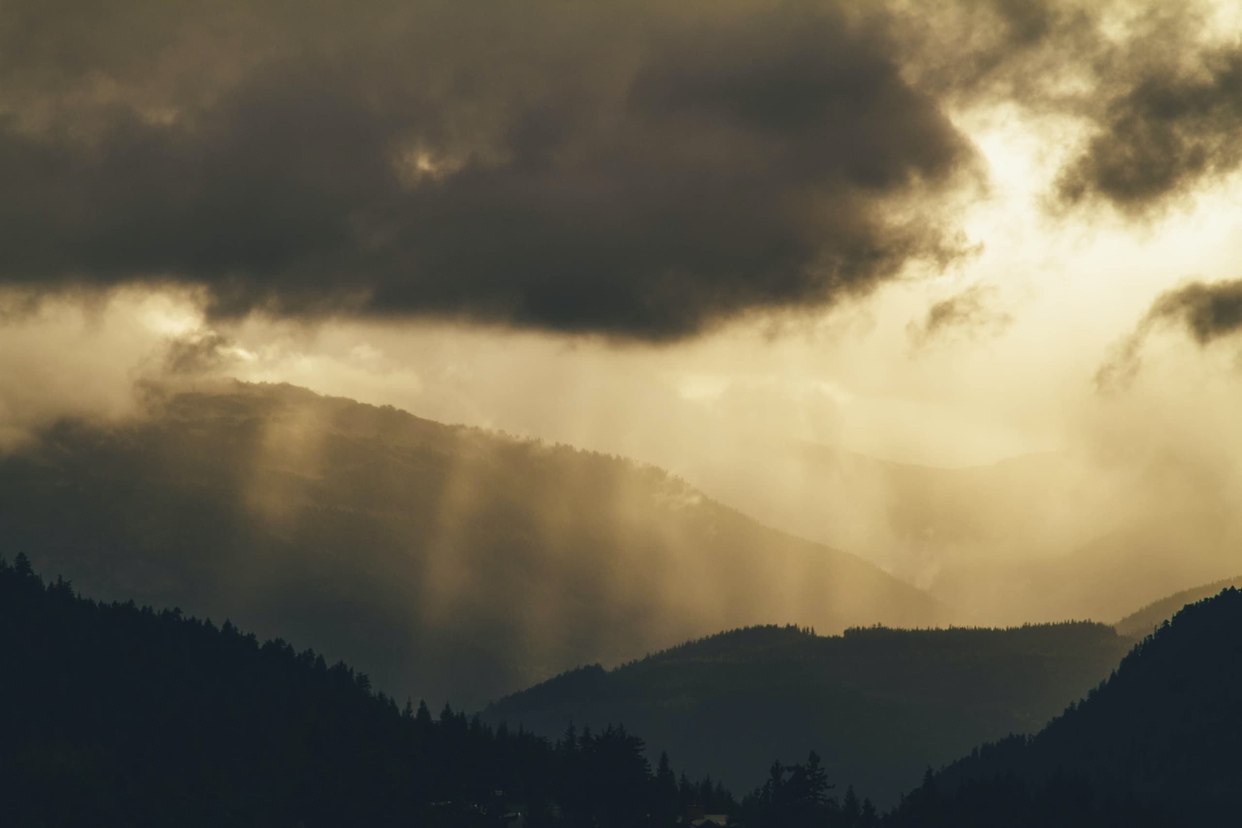 Scenic mountain vista with sunbeams piercing storm clouds