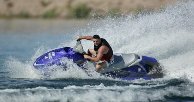 Solo rider on purple jet ski carving waves on open water
