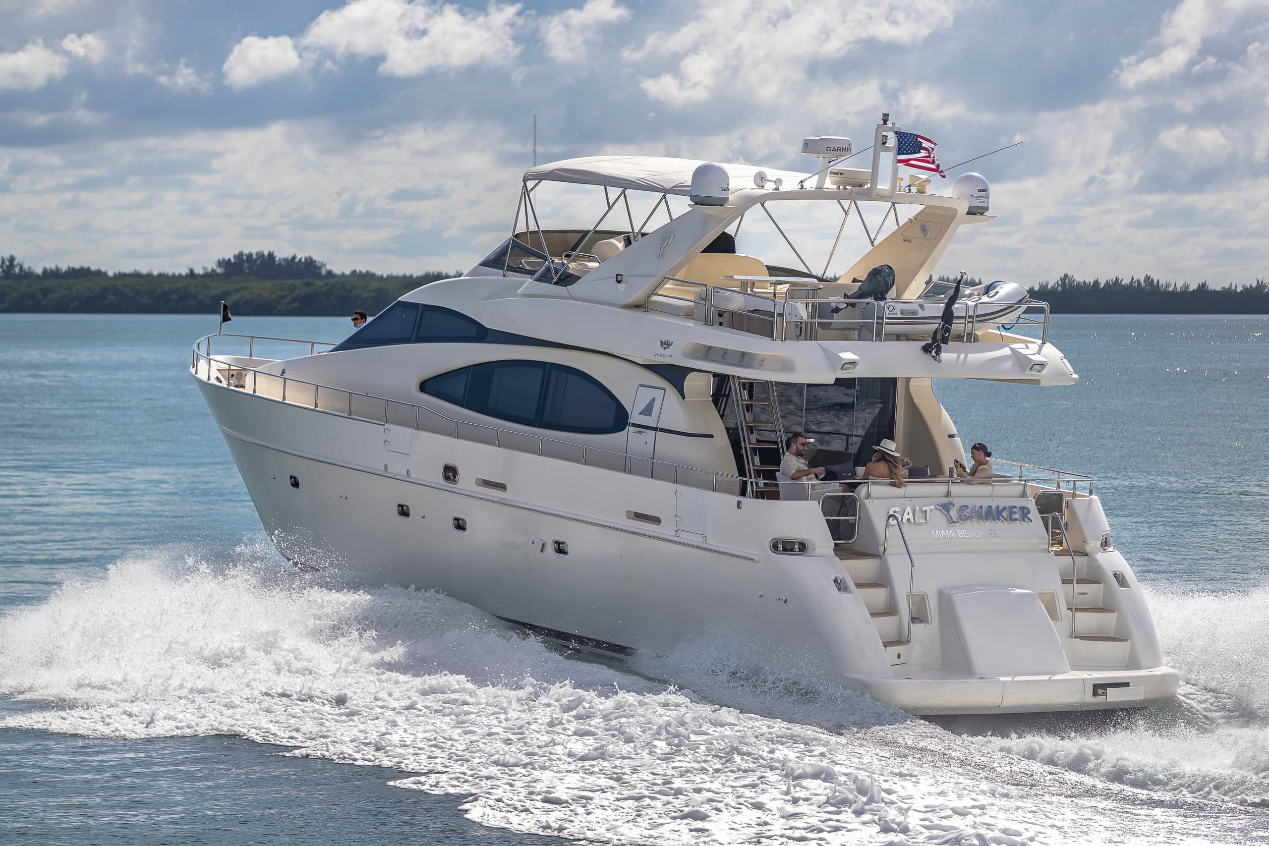 Motor yacht cruising on open ocean with wake and blue sky