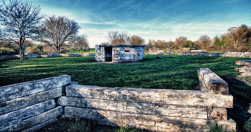 Paintball field landscape with wooden bunkers under blue sky