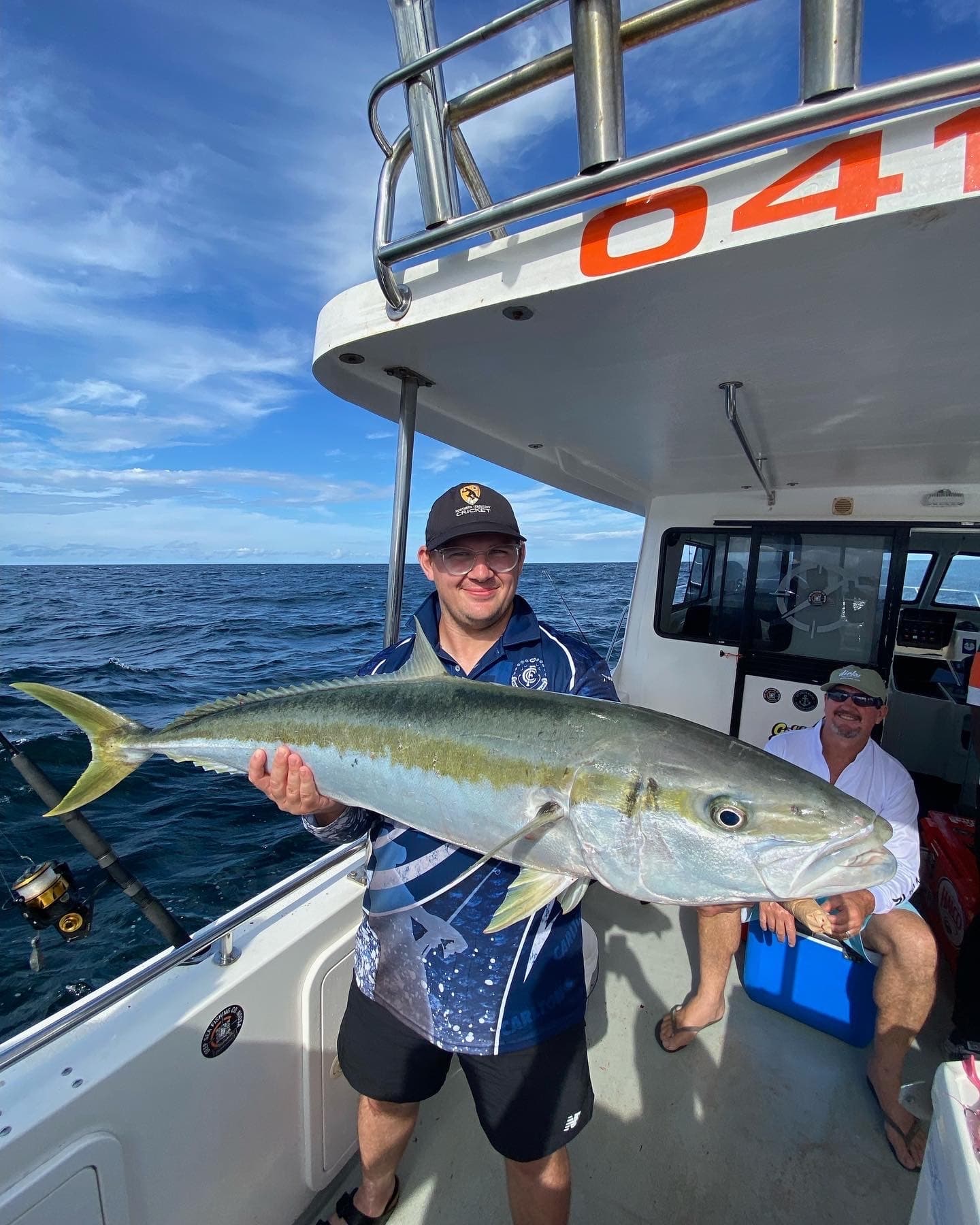 Angler holding large yellowtail on boat offshore Sunshine Coast
