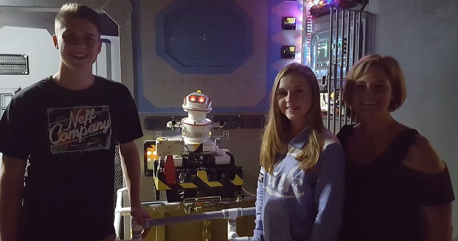 Family posing with interactive robot exhibit inside studio