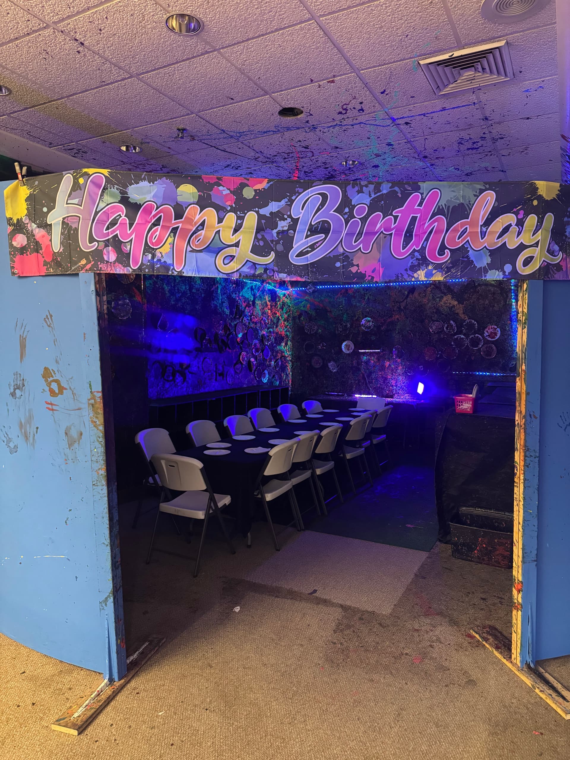 Indoor party room with 'Happy Birthday' banner and folding tables