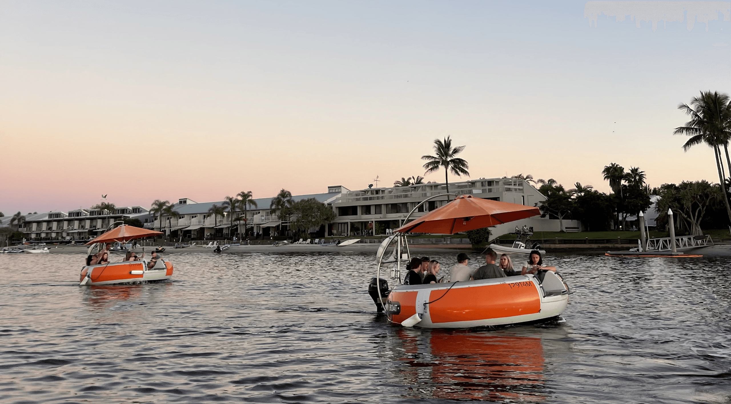 Round pontoon boats cruising at sunset along coastal waterfront
