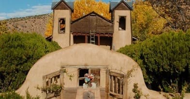 Historic adobe church at pueblo village framed by autumn trees