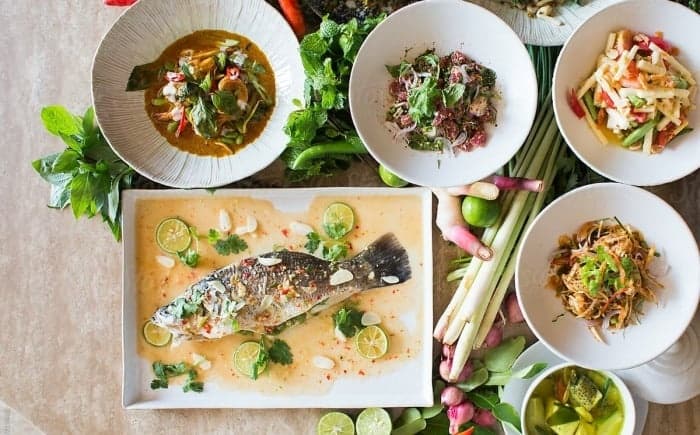 Whole baked fish with bowls and herbs for shared dining demo