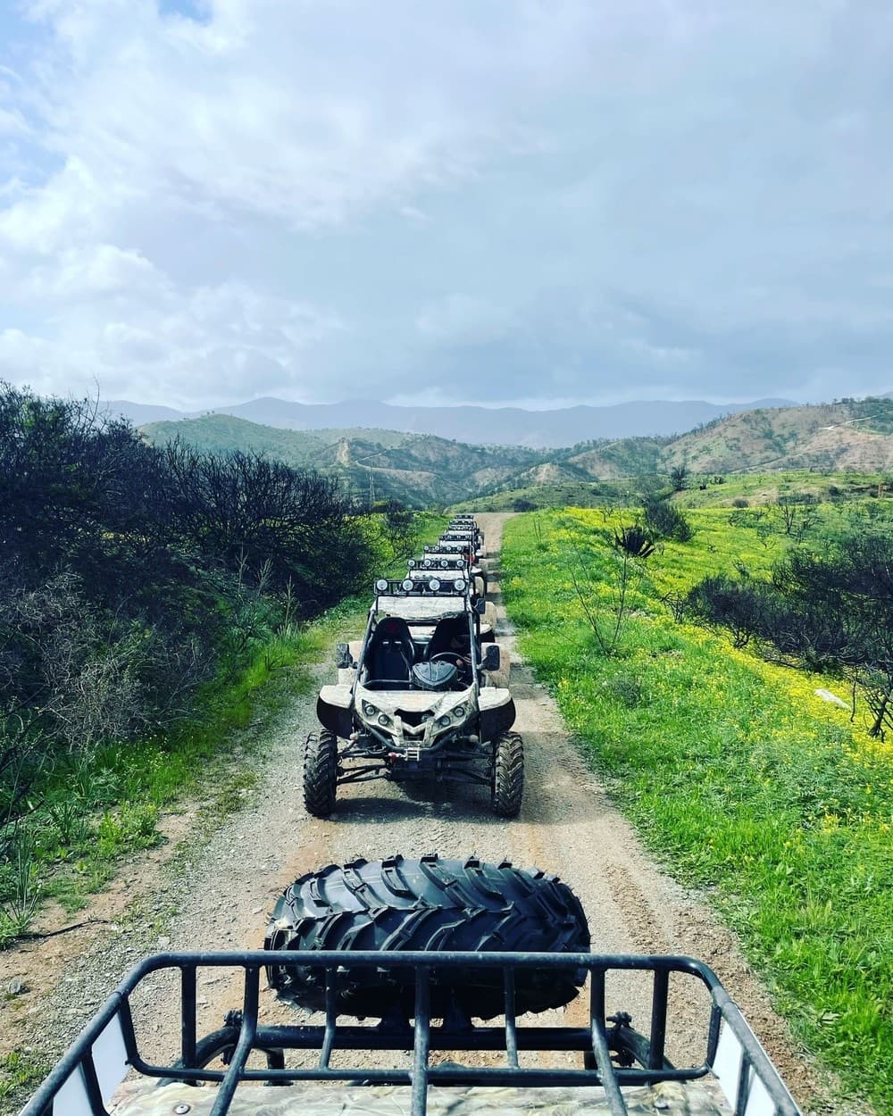 Line of ATVs on scenic hillside trail with mountain views