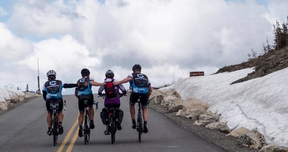 Group of cyclists climbing snowy mountain road, alpine ride