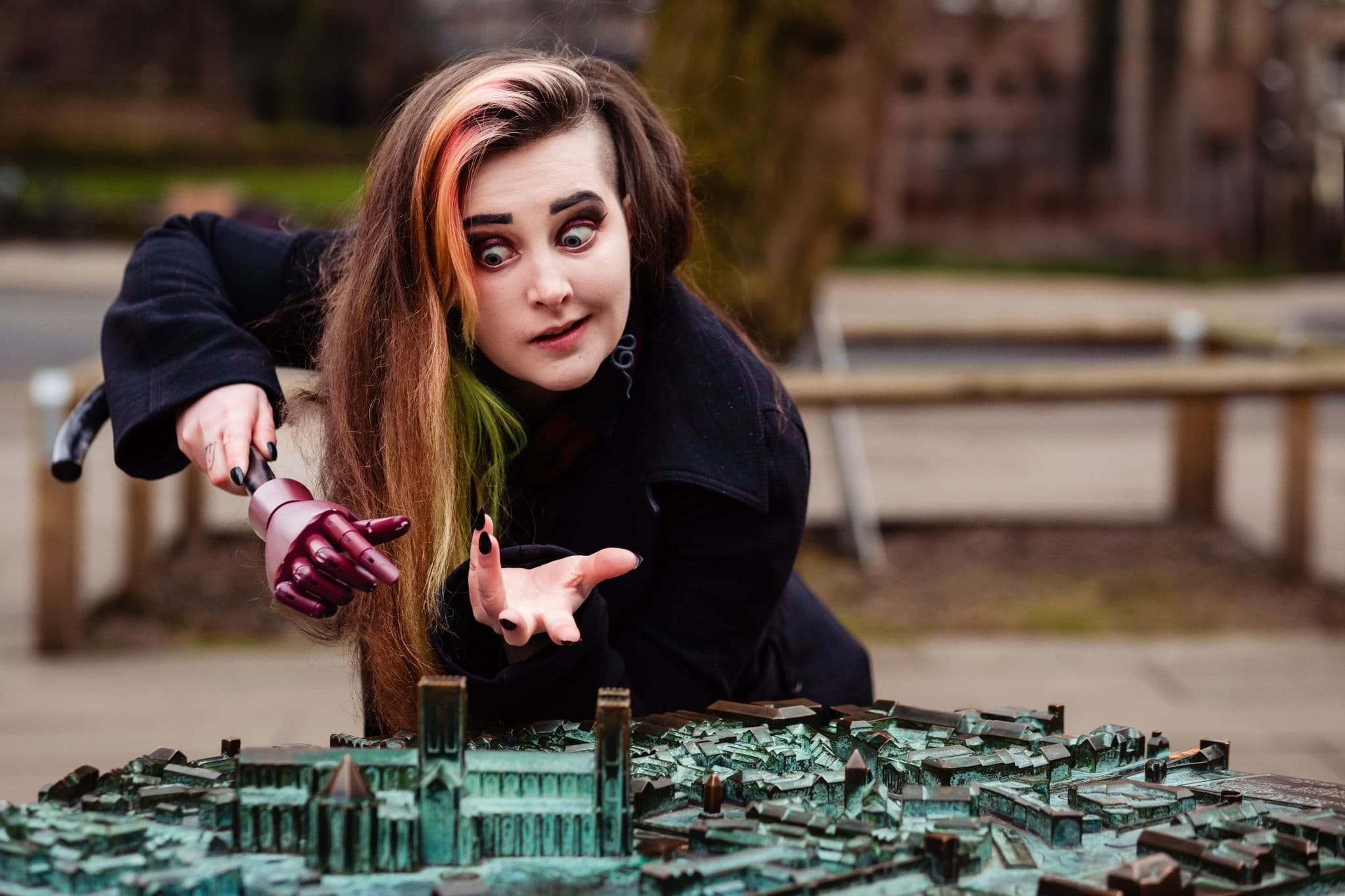 Woman examining bronze city model at outdoor park, interactive tour
